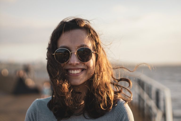 A girl smiling with sunglasses on.