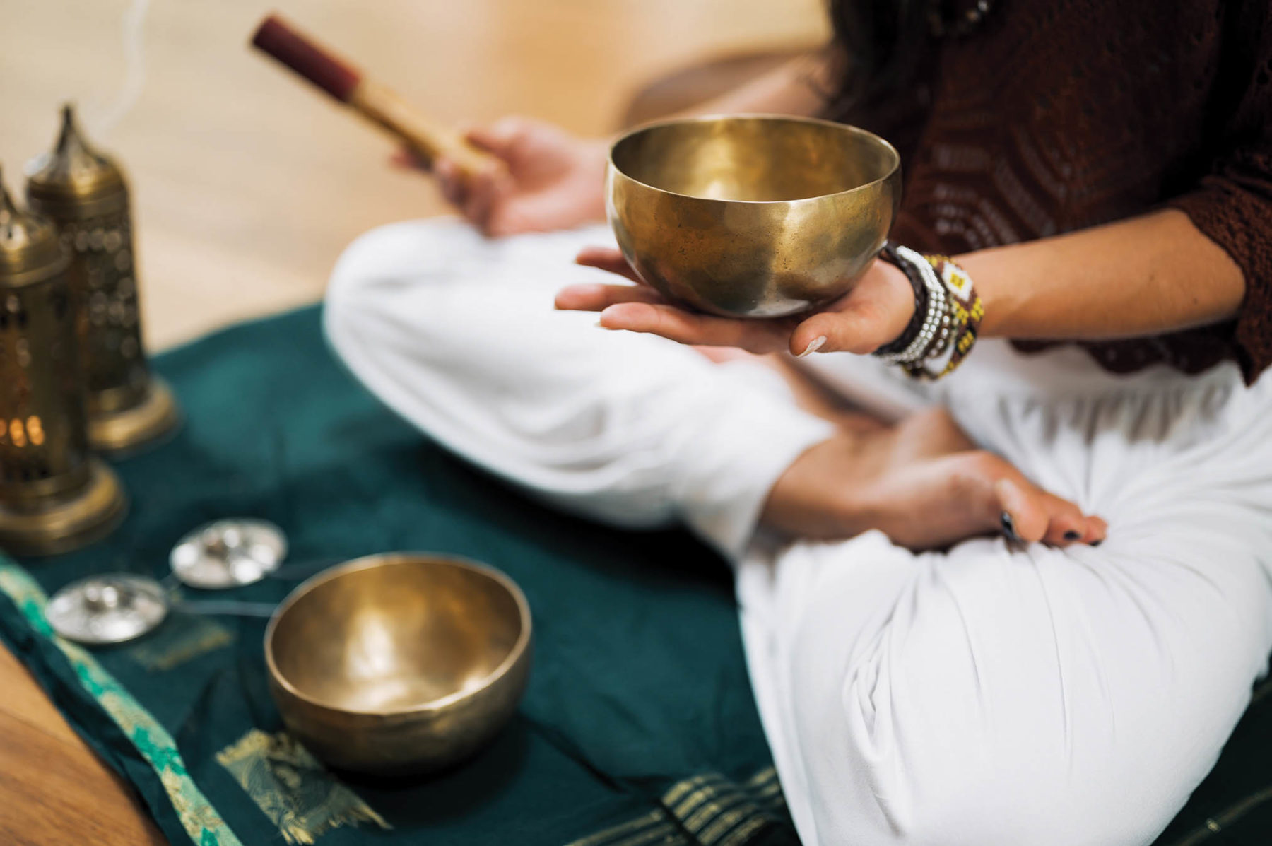 Someone sitting criss-cross and holding one of the sound bath bowls.