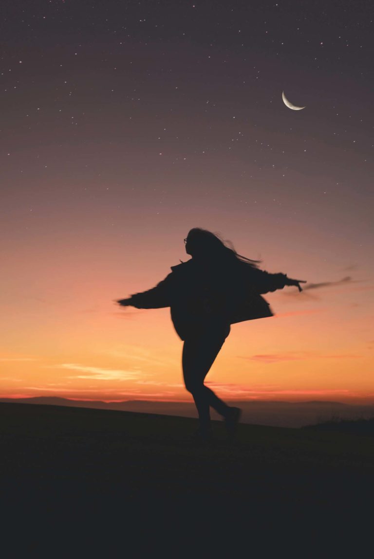 A person dancing in front of the sunset.