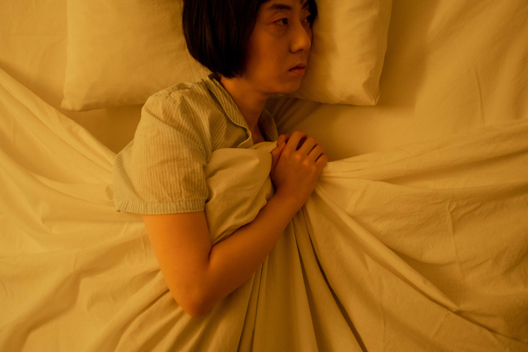 A woman laying in bed looking depressed.