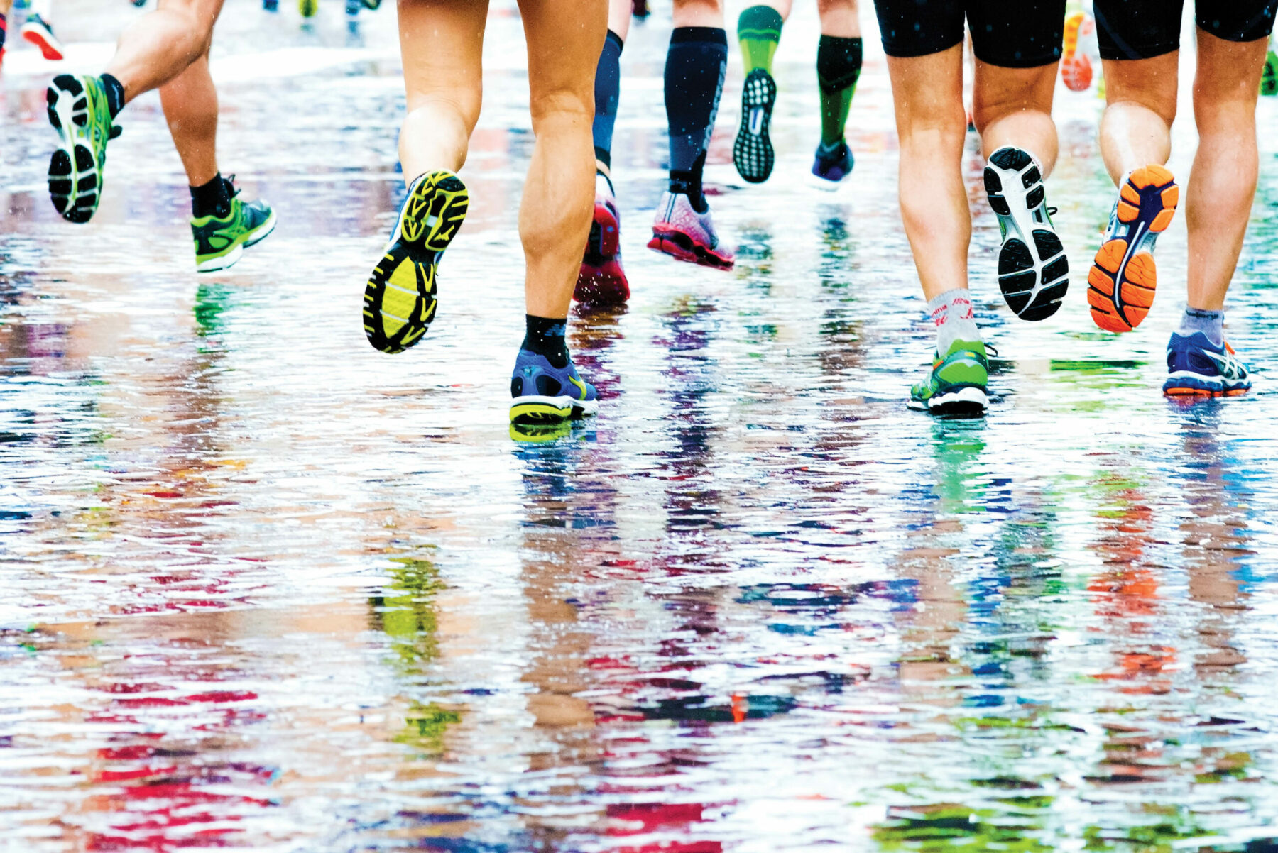 people running in a marathon on a wet surface.