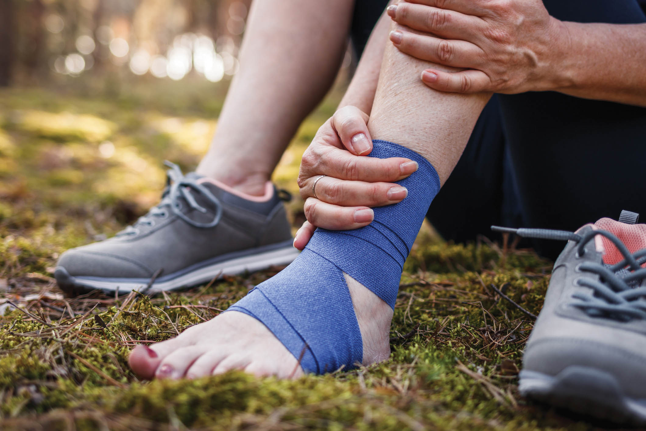 Sprain ankle during hiking in nature. Woman feeling pain after accident injury outdoors.