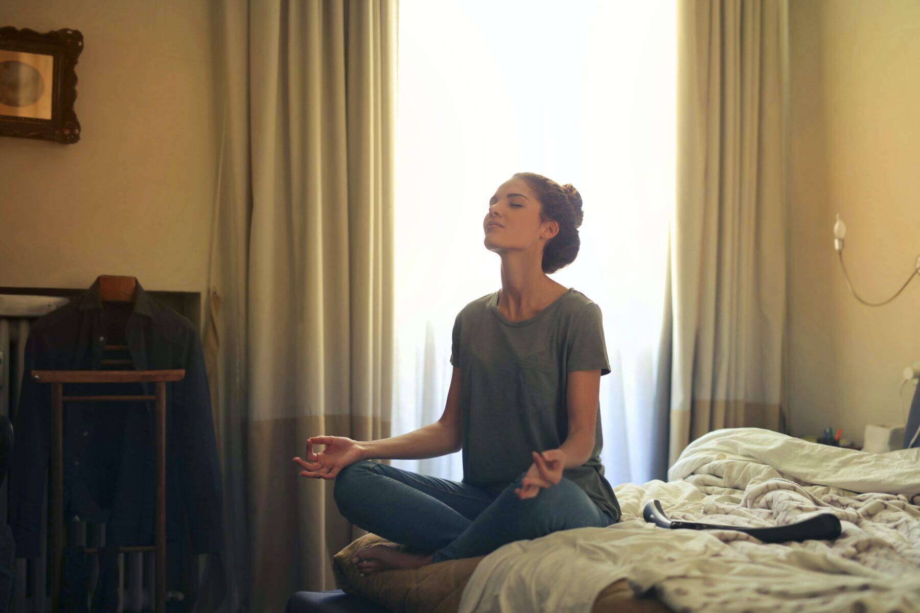 Woman in bedroom meditating.