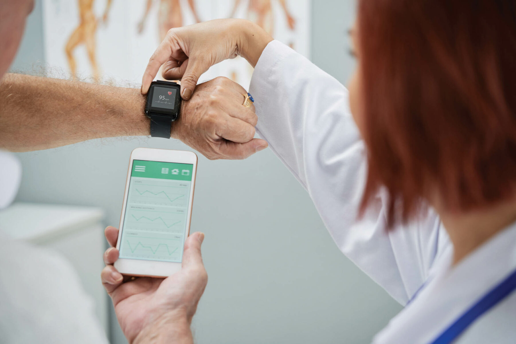 Doctor showing senior patient how to synchronize health app in smartphone and smartwatch.